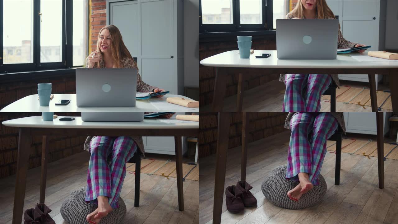 在家工作。倾斜年轻的金发女老板穿着睡衣裤子在网上工作使用笔记本电脑视频电话会议。