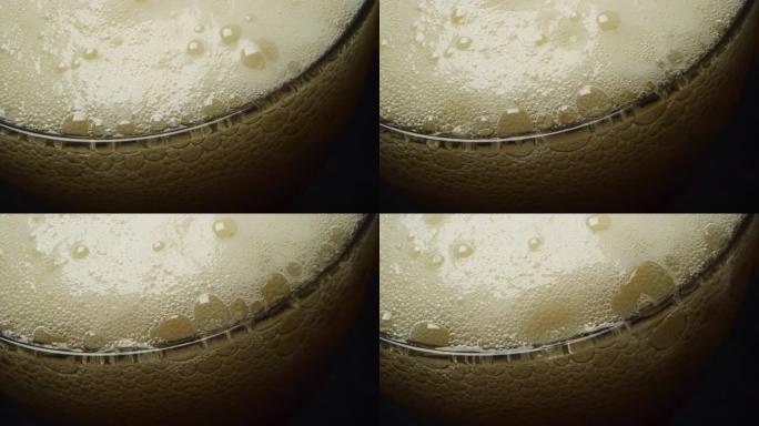 在黑色背景上有一个漂亮的白色泡沫的玻璃杯中关闭一些啤酒。概念: 饮食，宏观。