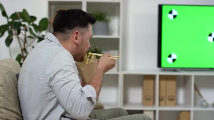 高加索男子在家看电视吃炒锅面