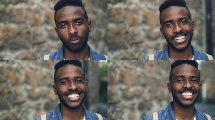 情绪激动的非洲裔美国男子的特写慢动作肖像笔直地看着相机，然后开心地微笑着对好消息做出反应。人和情感概
