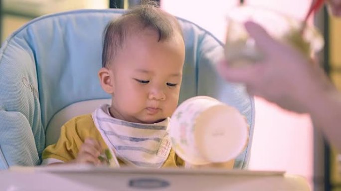 过度进食: 婴儿用勺子吃婴儿食品。