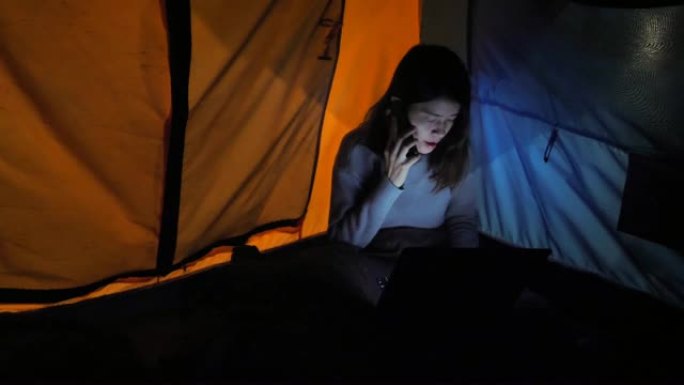 时髦的女人在森林露营时使用技术