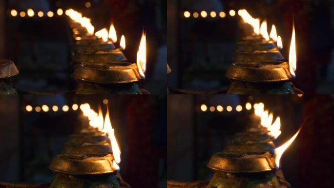 BOKEH: 美丽的小火焰在寺庙的油蜡烛内闪烁