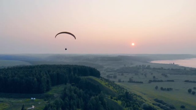 一名运动员在日落背景下用滑翔机飞行。滑翔伞，动作，极限运动概念。