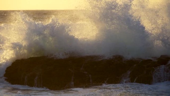 葡萄牙的大西洋海浪击中了一块黑色的岩石。在暴风雨的天气中，日落时被大量泡沫覆盖的水域。UHD