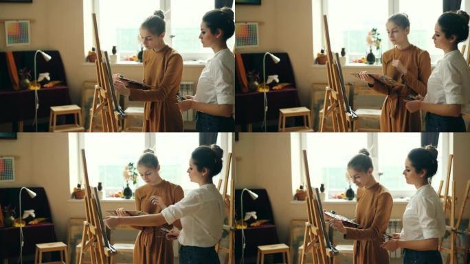 开朗的艺术系学生正在用画笔在画布上绘画，而她的老师正在检查她的作品并帮助她。女孩微笑着享受课堂。