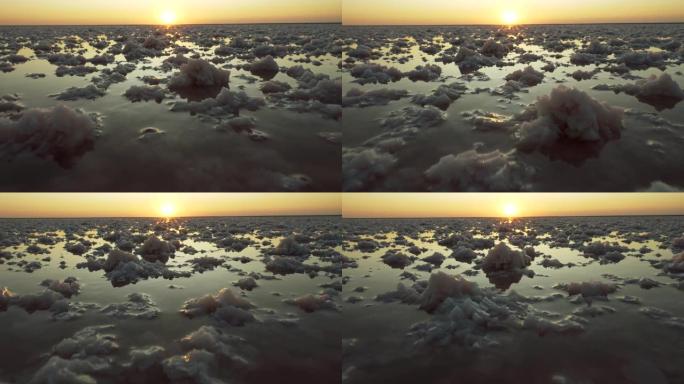 日落时盐湖中的盐堆。背景中的夕阳。4K