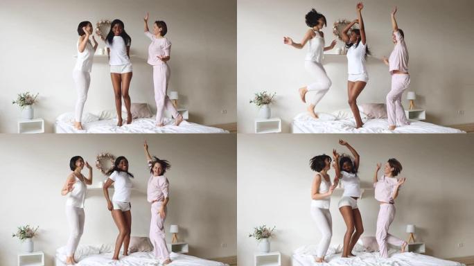 三个无忧无虑的多样化女士穿着睡衣在床上跳跳舞