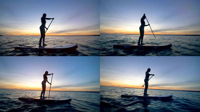 苗条的女士正穿着桨板在开阔的水面上航行。夏季趣味动作运动。