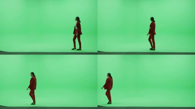 绿屏色键工作室: 穿着时尚红色西装的美丽女商人从右到左穿过房间。侧视图摄像机拍摄