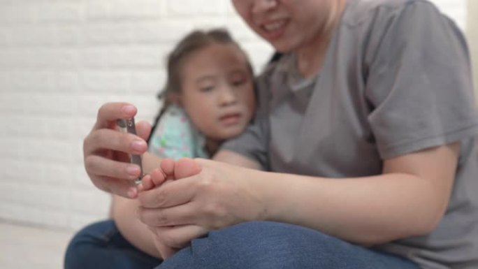 妈妈正在为女儿剪脚趾甲