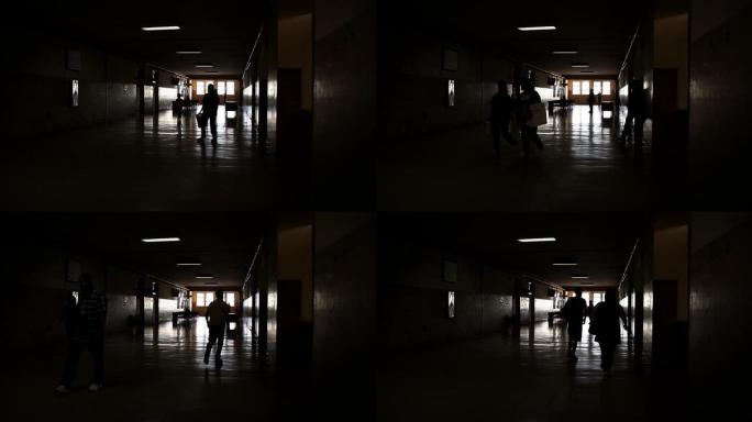 穿过黑暗走廊的人们轮廓的背光视图。