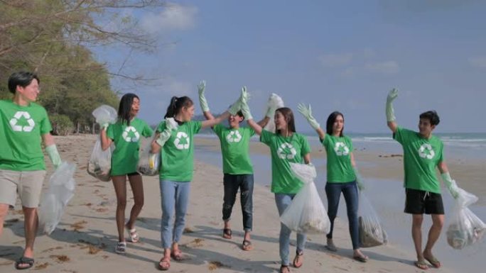一群快乐的志愿者，在海滩上有垃圾袋清洁区。志愿服务，慈善，清洁，人和生态理念