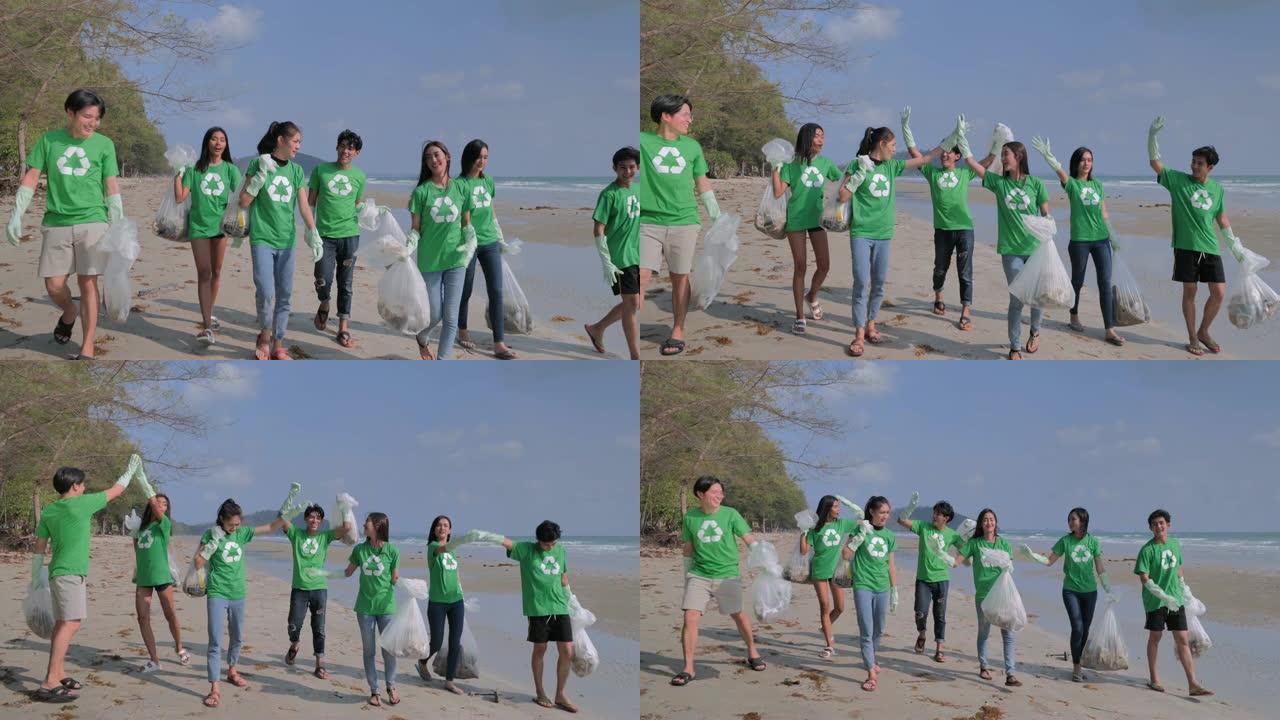 一群快乐的志愿者，在海滩上有垃圾袋清洁区。志愿服务，慈善，清洁，人和生态理念