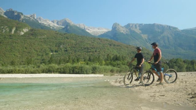 慢动作: 两个家伙骑自行车上一条小溪，观察风景。