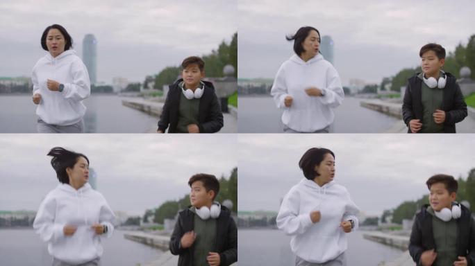 亚洲母亲和儿子在城市的河边奔跑