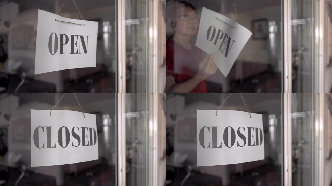 亚洲高级女性在商店门上的开放标志变为关闭标志
