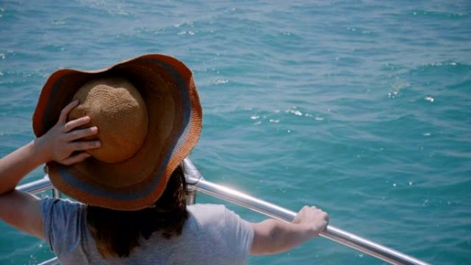 美丽的特写镜头，快乐兴奋的旅游女人戴着旧太阳帽，在海上游艇前面享受阳光航行。