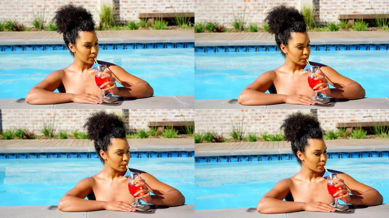 年轻混血女子在游泳池4k喝鸡尾酒的前视图