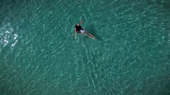 夏天，海滩上的一位美女在平静的海水中放松，海水清澈透明。