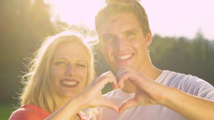慢动作: 幸福的夫妻一边看着镜头，一边做一个心脏符号。