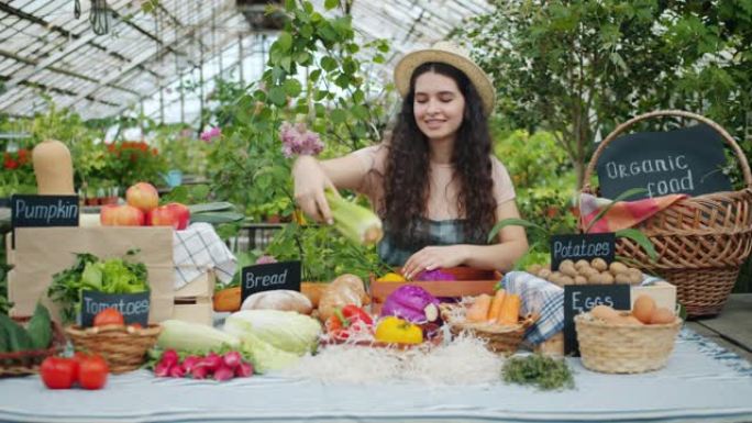 围裙里快乐的女农民在市场上微笑着把有机食品放在桌子上