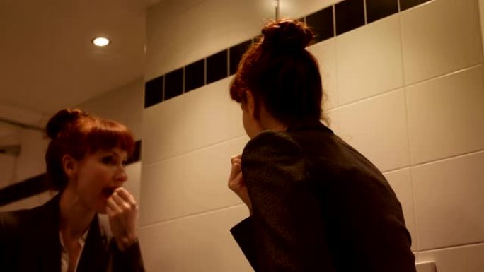 在4k酒店，中年白人女商人在镜子前的嘴唇上涂口红