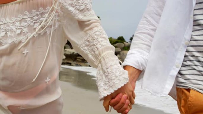 情侣在海滩上手拉手行走的中段4k