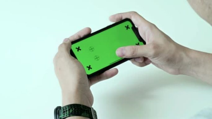 男人在家使用、滚动和查看带色度键的智能手机绿屏