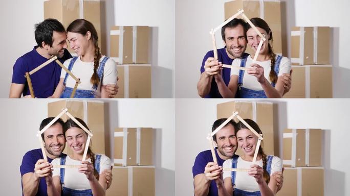 一对刚刚买房并正在搬家的恋爱夫妇的肖像。新娘和新郎微笑着，手里拿着房子形状的仪表。