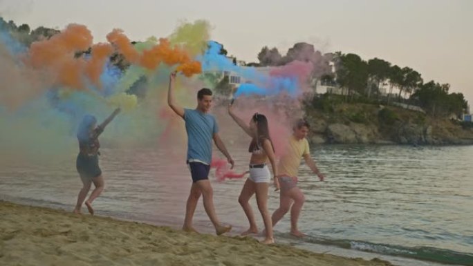 日落时，年轻的朋友在海滩上玩彩色烟弹