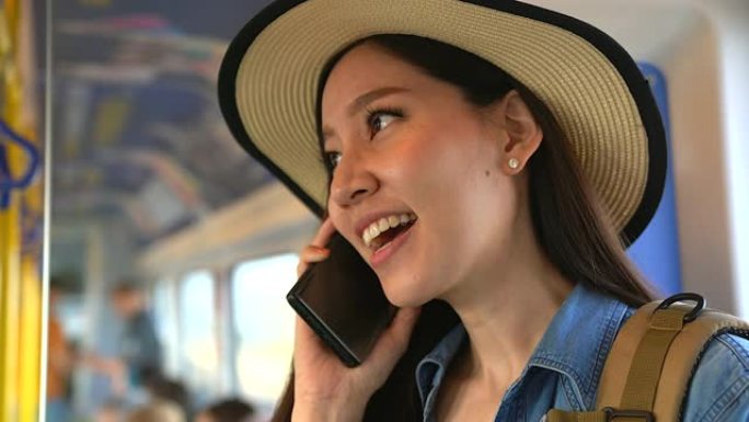 年轻的休闲女子在火车上用智能手机聊天。