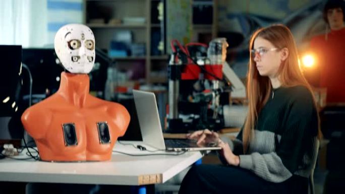 科学家机器人与笔记本电脑一起工作，控制机器人。与未来派人形机器人合作的工程师。