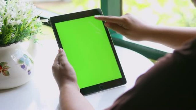 特写女性手持空白平板电脑，绿屏