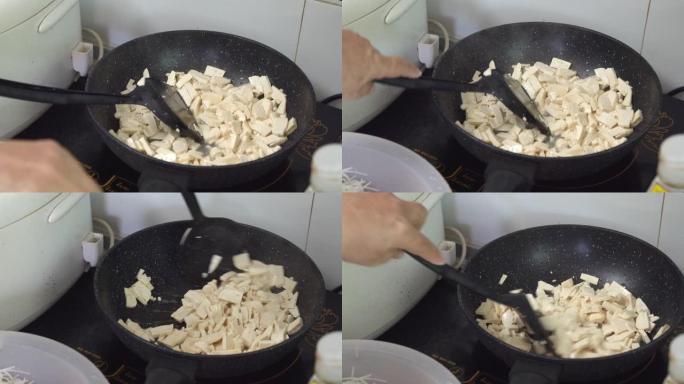 亚洲妇女在厨房的平底锅上手工煎豆腐。