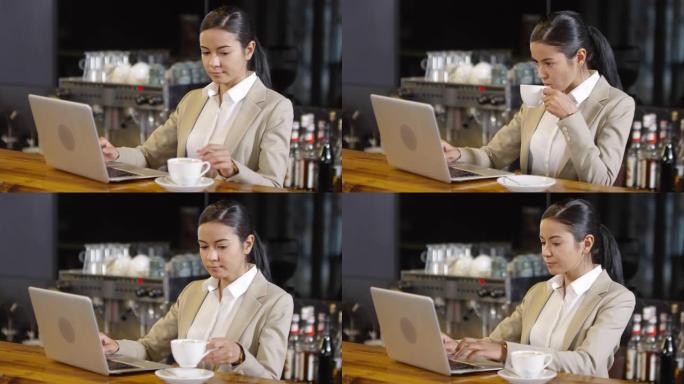 亚洲商务女士在咖啡馆的酒吧柜台用笔记本电脑喝咖啡