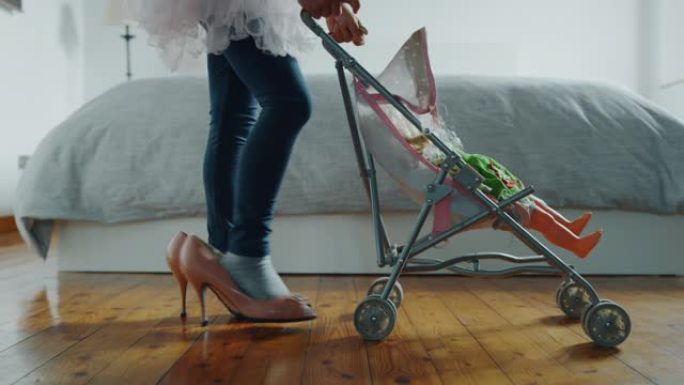 小女孩穿着妈妈高跟鞋玩婴儿车玩具和洋娃娃的正宗镜头
