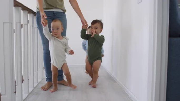 无法辨认的女人在家中用手带领亚洲婴儿三胞胎