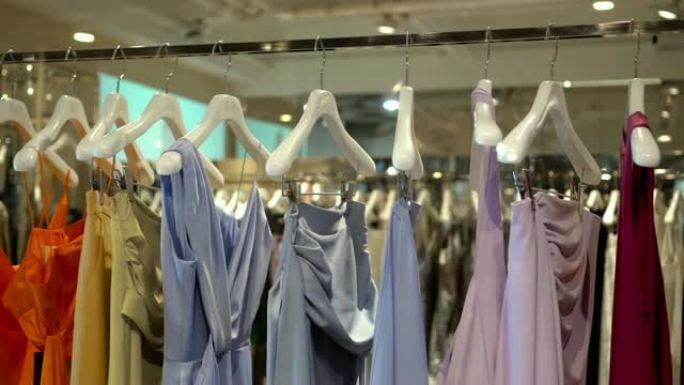 在百货商店，购物中心和服装概念的时尚服装店中，衣架上的衣架和栏杆的4k镜头场景