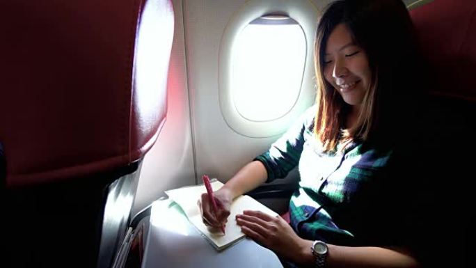 4k镜头有吸引力的亚洲女性旅行者在飞机，交通和乘客旅行概念上写日记和日记的场景