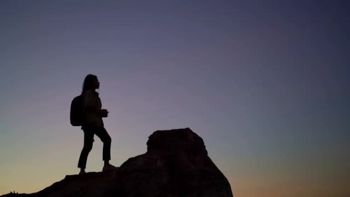 女摄影师在太阳升起前在山顶上拍照