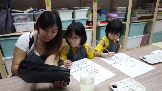 一名亚洲中国女美术老师在美术课上教2名中国女青年学生水彩画和着色