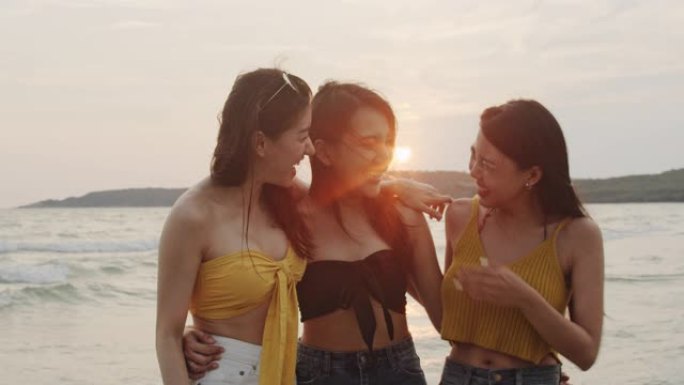 一群亚洲女性一起聊天，在海滩上享受有趣的时刻，美丽的女性在日落时在海边的海滩上放松。女人在夏天的海滩