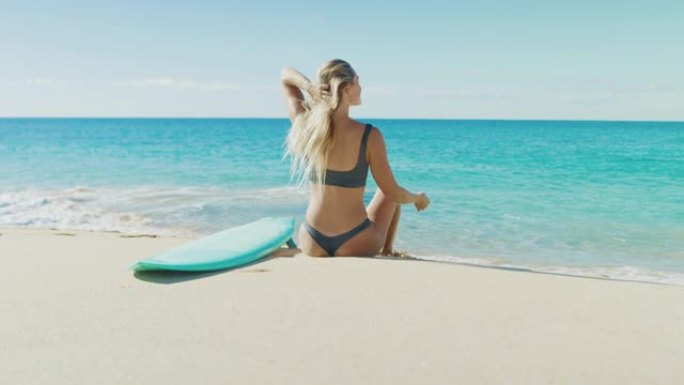 快乐健康的冲浪女人坐在沙滩上