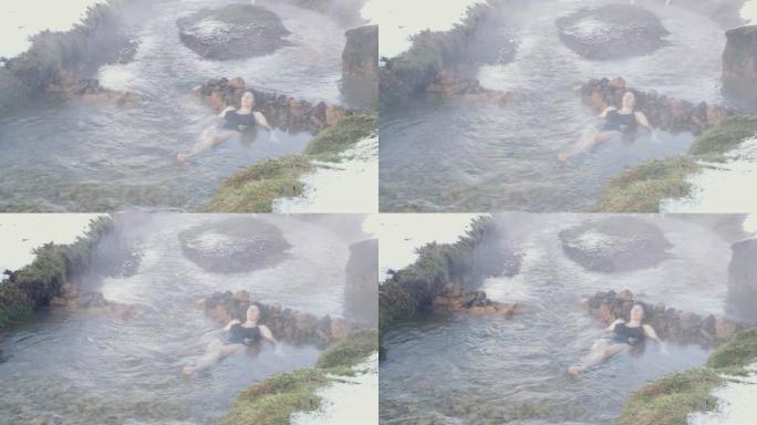 穿着泳衣的宁静女士浸泡在冰岛的温泉中