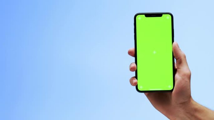 一只手拿着黑色手机，桌面屏幕为空白绿色