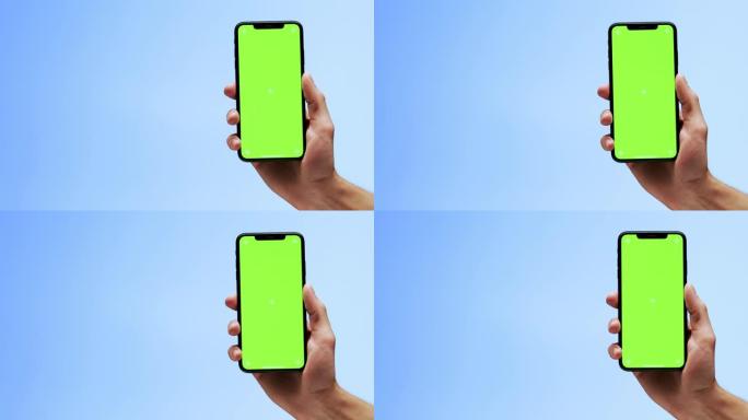 一只手拿着黑色手机，桌面屏幕为空白绿色
