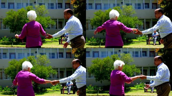 活跃的混血高级夫妇在养老院4k花园中跳舞的侧视图