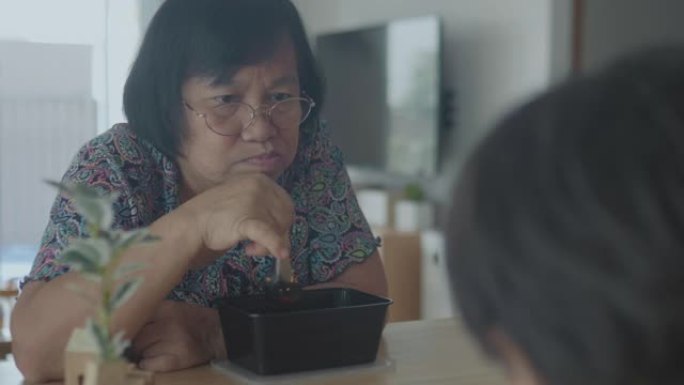 祖母和孙女在厨房餐桌上吃面条