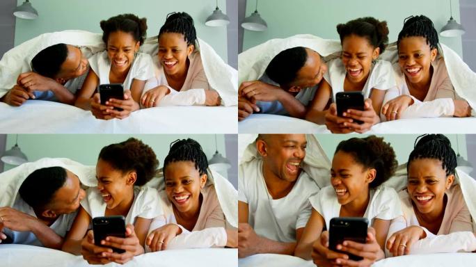 快乐黑人家庭在舒适的家庭4k床上使用手机的前视图